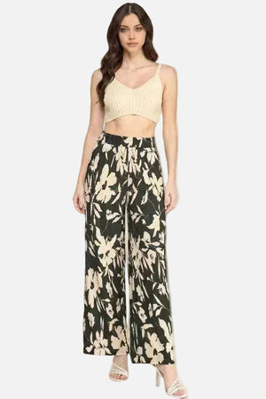 Woman wearing a beige top and black floral wide-leg pants on a white background