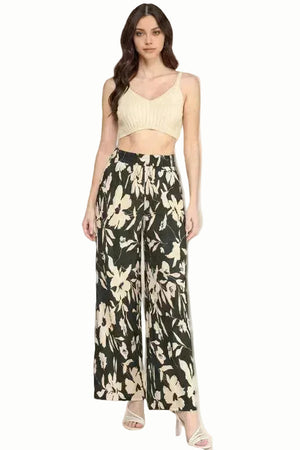 Woman wearing a beige top and black floral wide-leg pants on a white background
