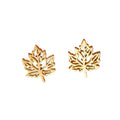 Gold leaf-shaped earrings held between fingers on a white background
