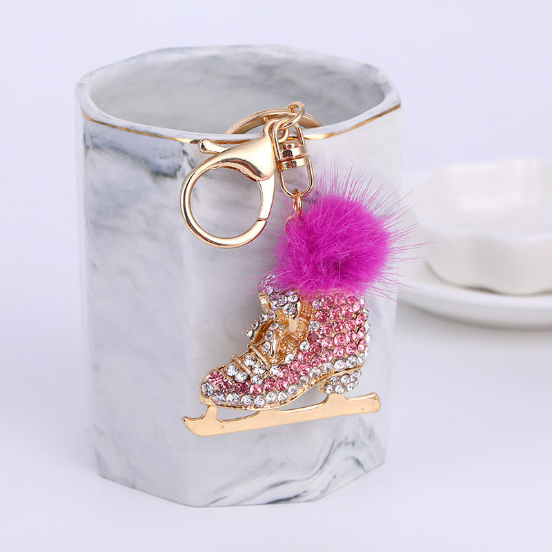 Pink crystal ice skate pom pom keychain on marble block – product shot