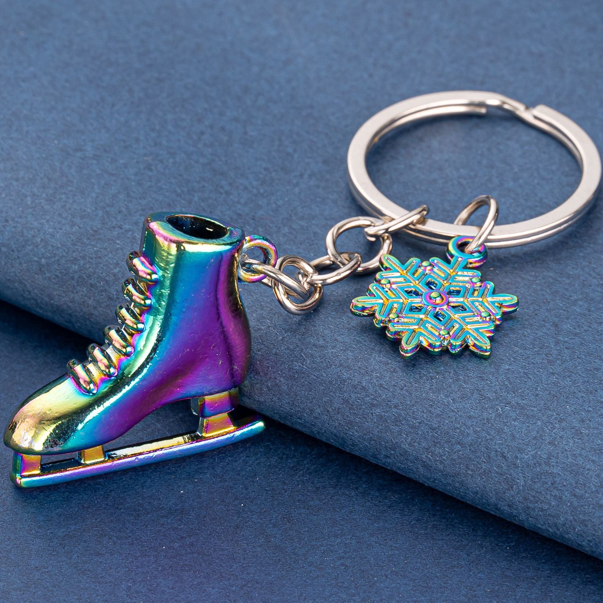 Colorful rainbow ice skate and snowflake keychain – close-up on blue background