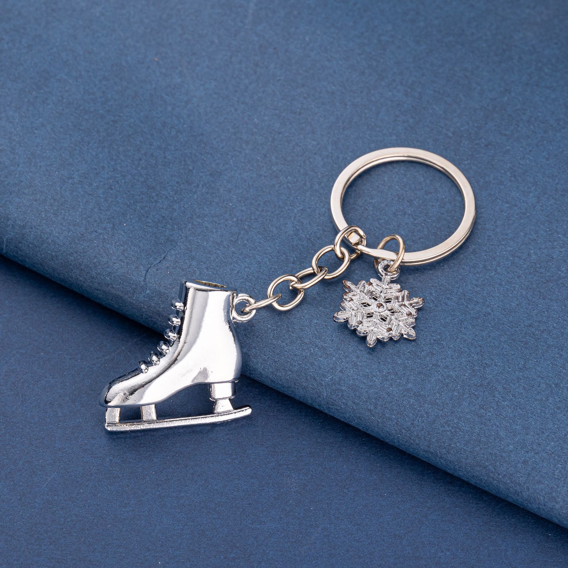 Silver ice skate and snowflake keychain on blue background