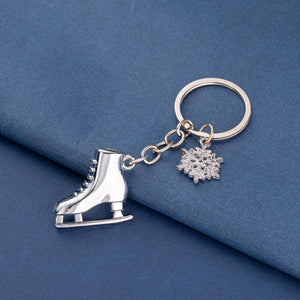 Silver ice skate and snowflake keychain on blue background