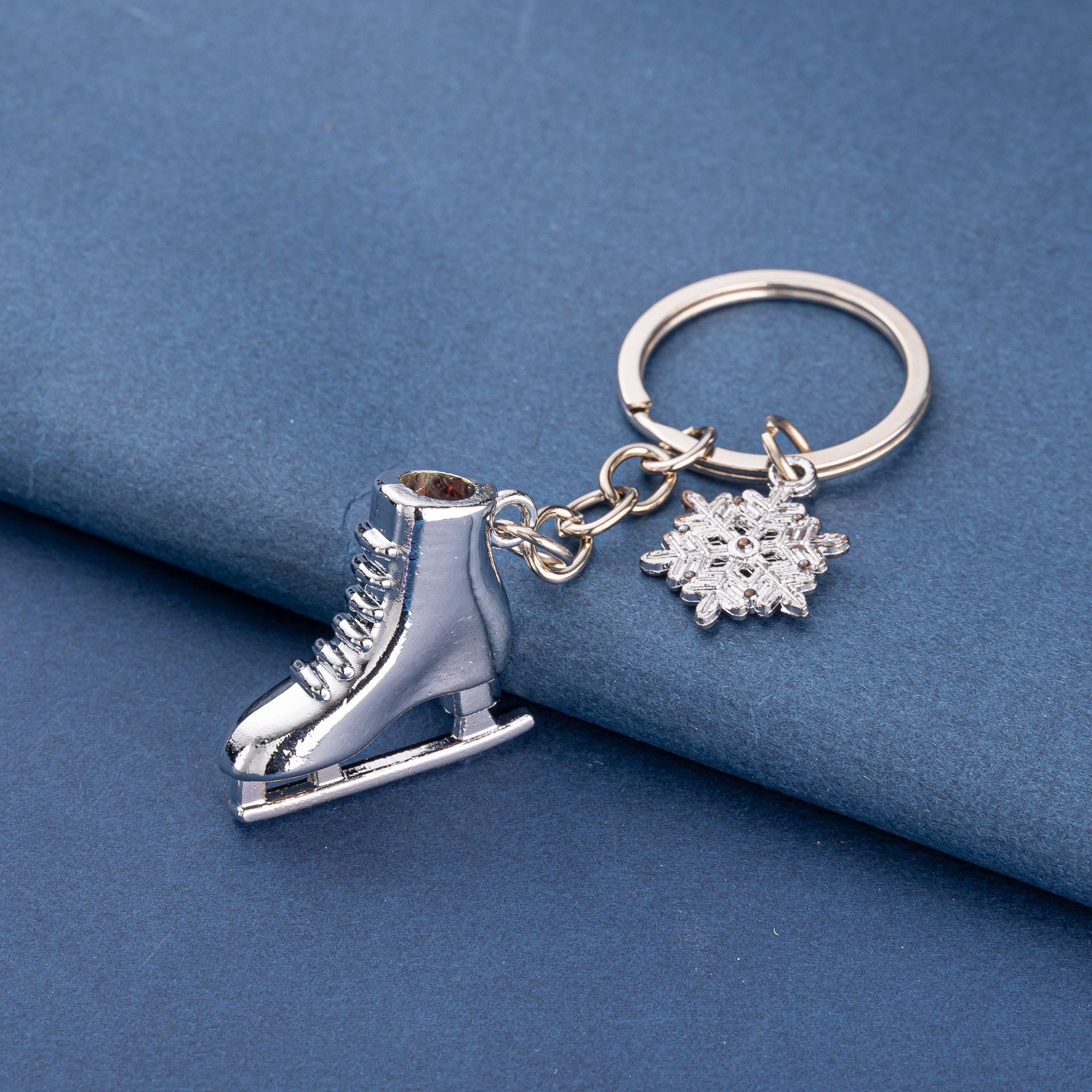Silver ice skate keychain – angled view on blue background
