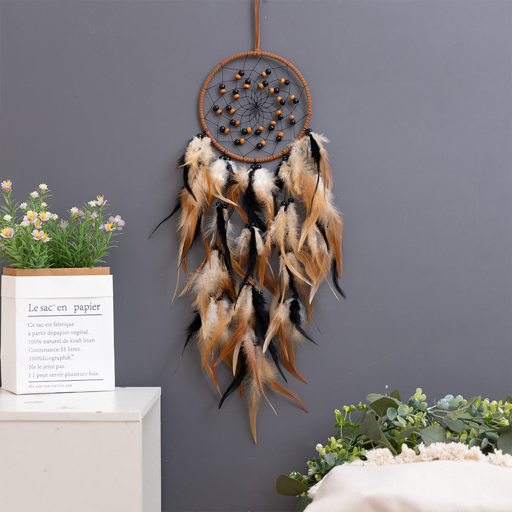 Dream catcher hanging on white wall with plants
