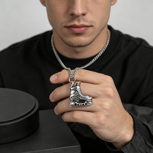 Ice skate pendant close-up on black surface with chain