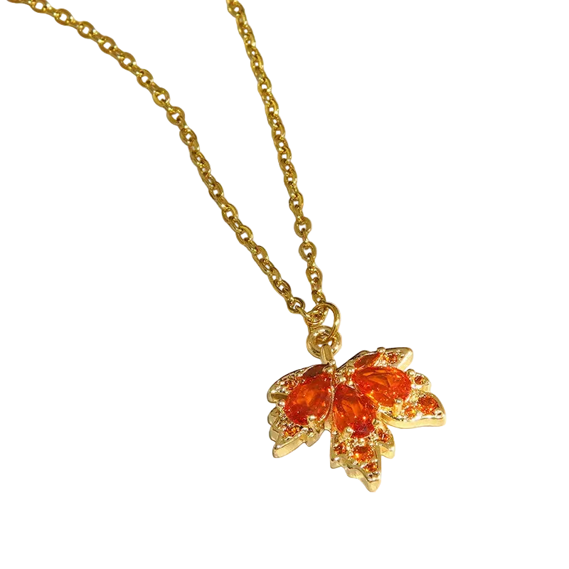 Gold chain necklace with a butterfly-shaped pendant featuring orange-red gemstones, displayed on a white surface.